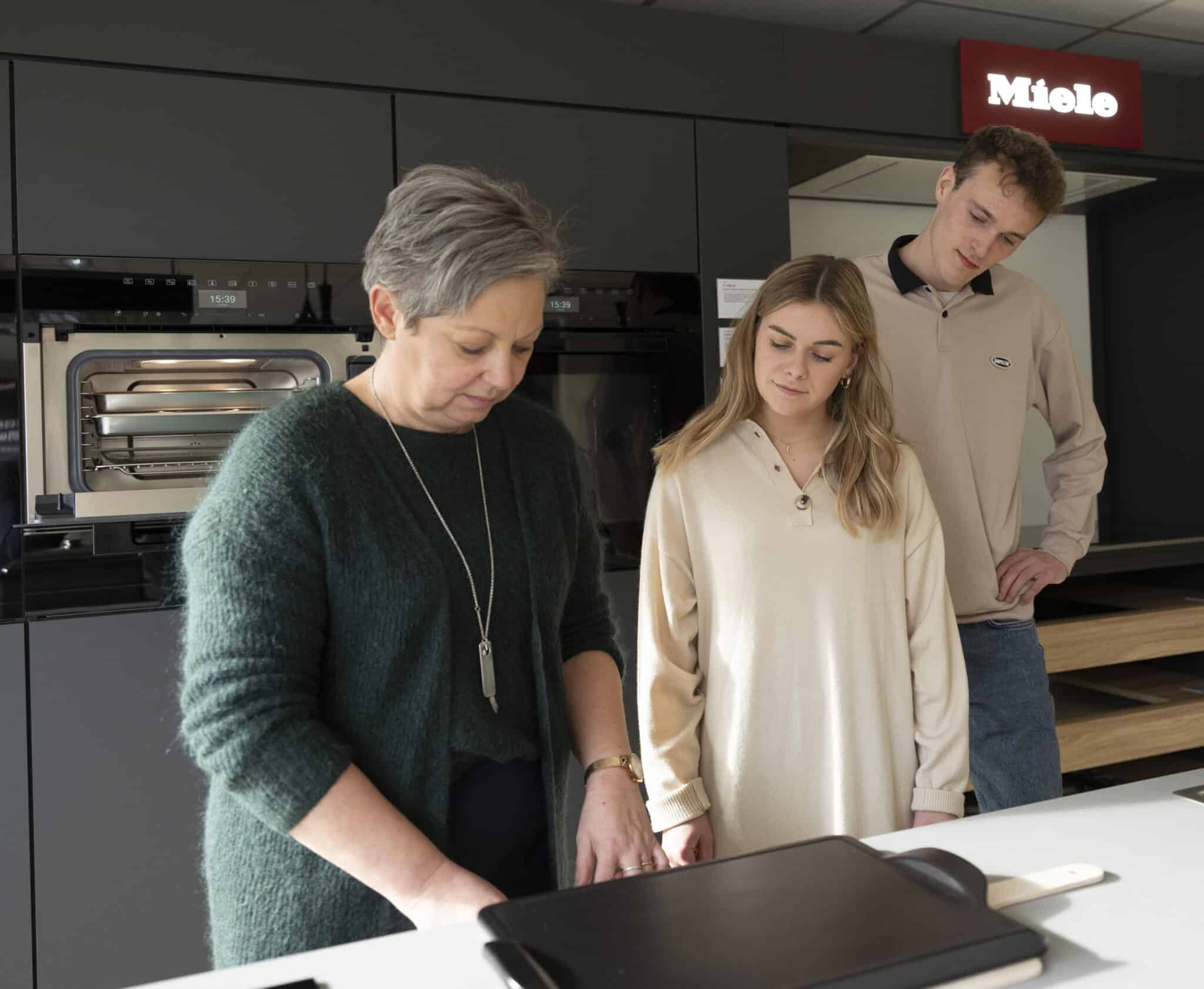 Marleen, de eigenares en verkoopster van Miele Center Bingé geeft uitleg en advies over inbouwtoestellen aan een jong koppel